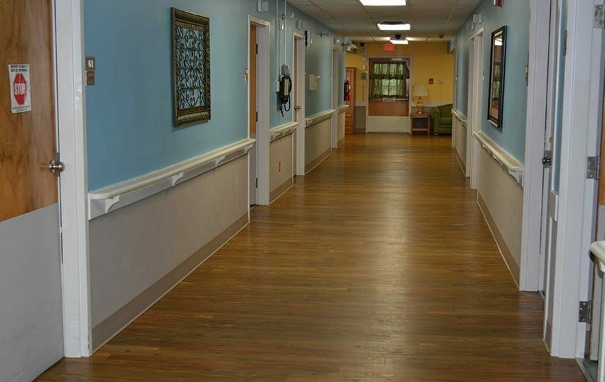 A long hallway with wooden flooring and several doors on each side.