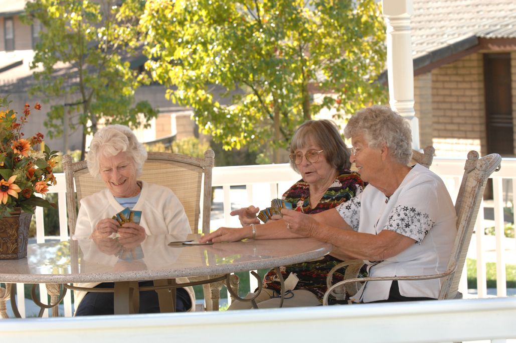 A group of elderly individuals enjoying a card game on a porch.