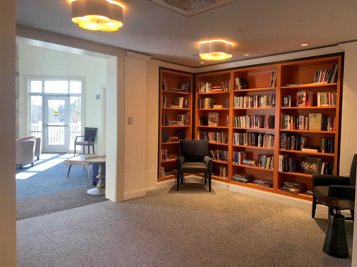 A cozy reading area with wooden bookshelves filled with books and a comfortable chair.