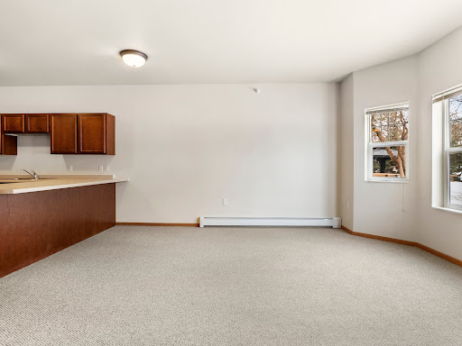 A spacious and airy open-plan living space featuring a kitchen area with wooden cabinets and ample natural light.