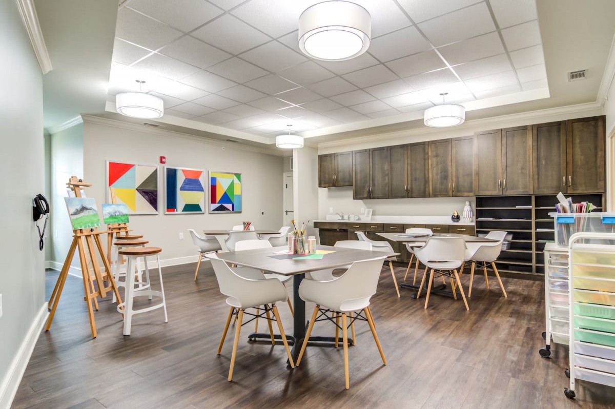 A modern office kitchen with a seating area and contemporary artwork.