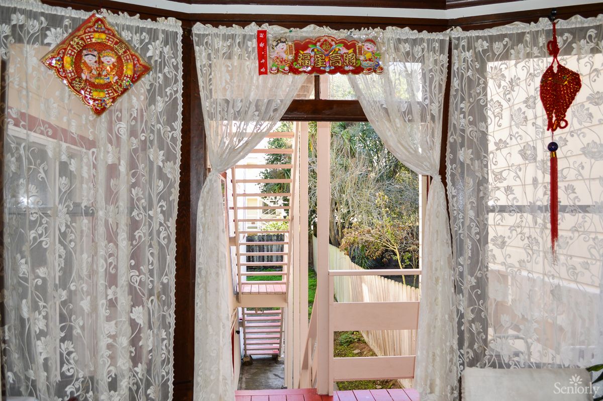 A cozy interior with lace curtains framing a doorway that opens to an outdoor view.