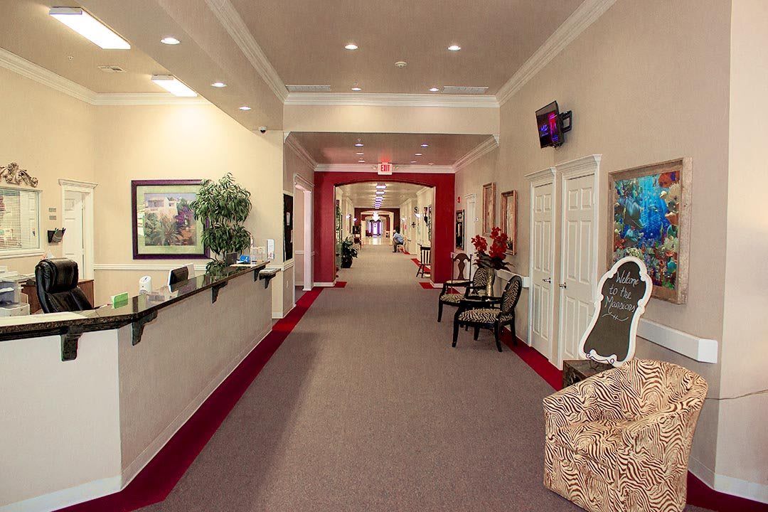 A well-lit hallway with red carpeting and decorated walls leading to various rooms.