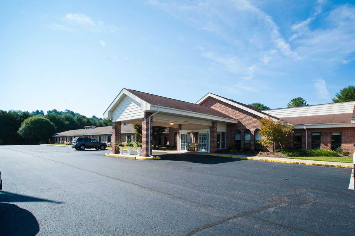 A single-story brick building with a covered entrance and adjacent parking lot.