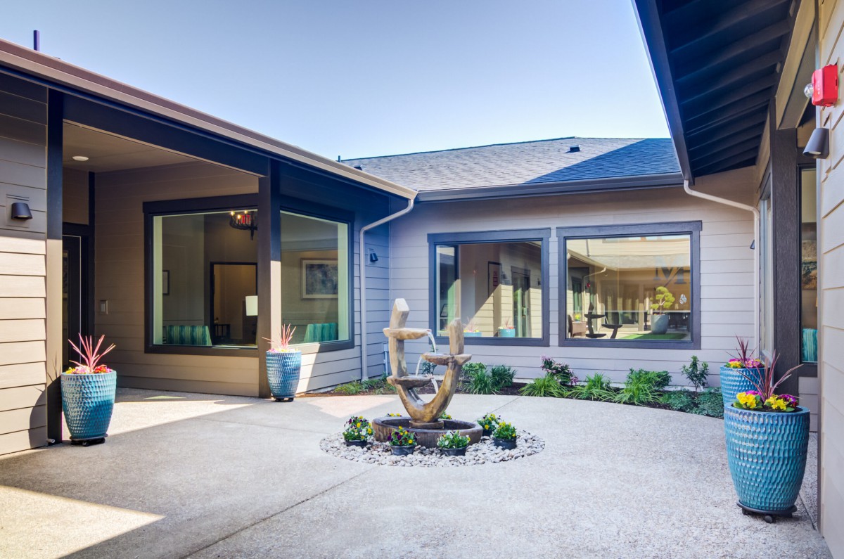 A serene courtyard featuring a fountain and large windows, creating a peaceful outdoor atmosphere.