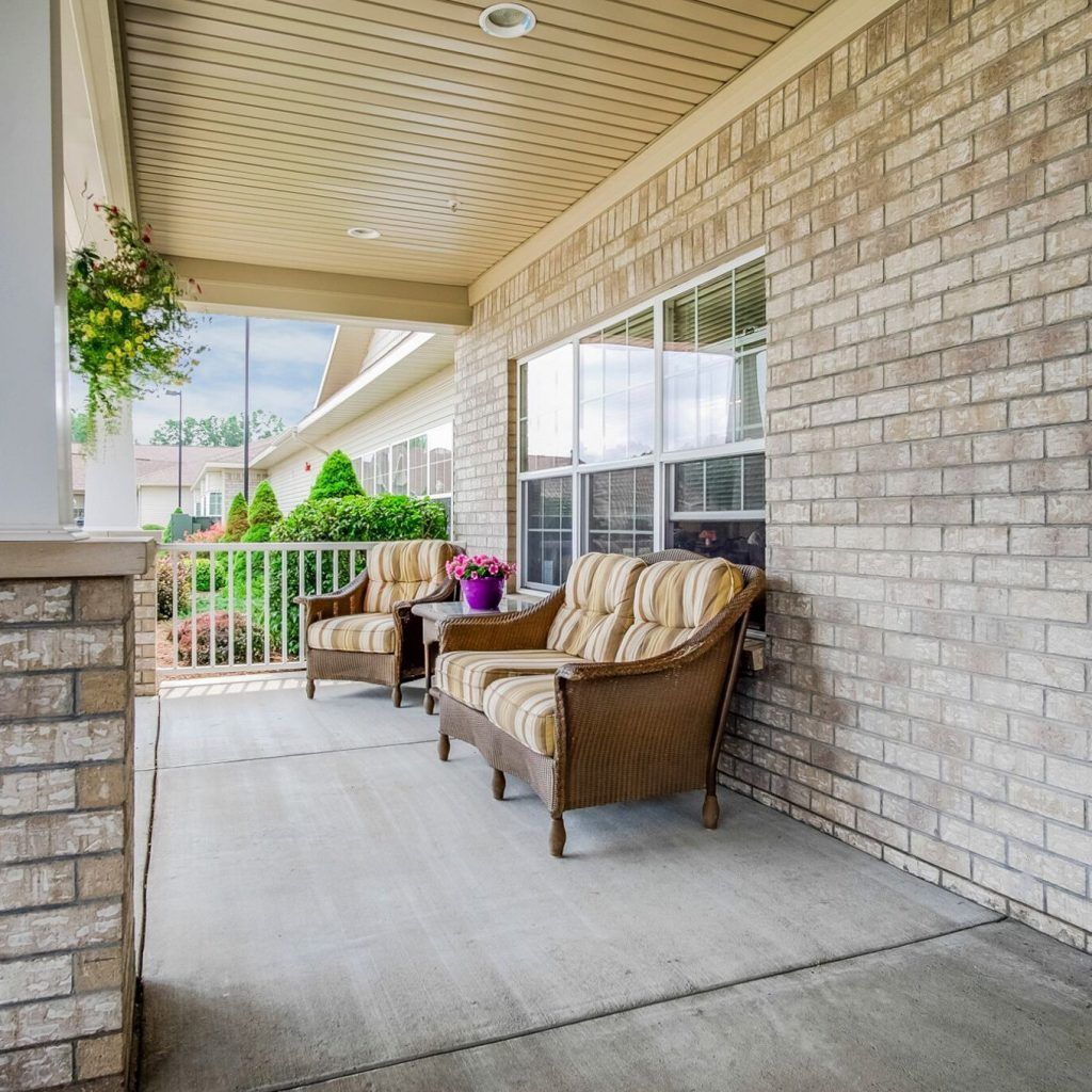 A cozy covered porch with comfortable seating and plants.