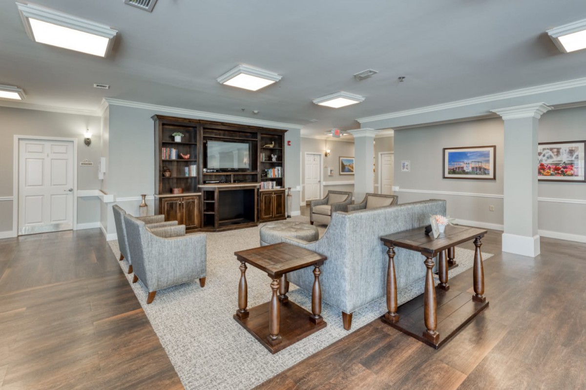 A spacious living room with modern furniture, including a sofa and coffee tables, centered around a fireplace and surrounded by bookshelves.