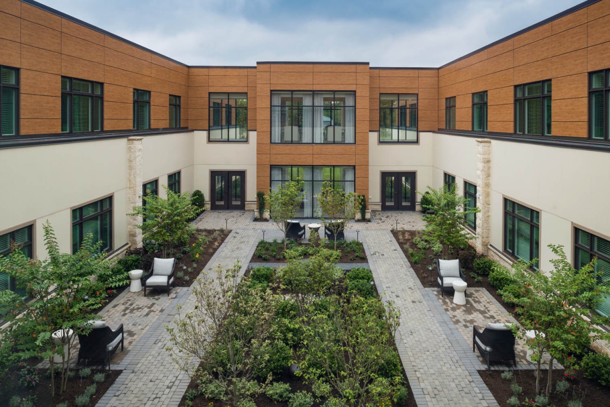 A modern courtyard featuring lush landscaping and outdoor seating.