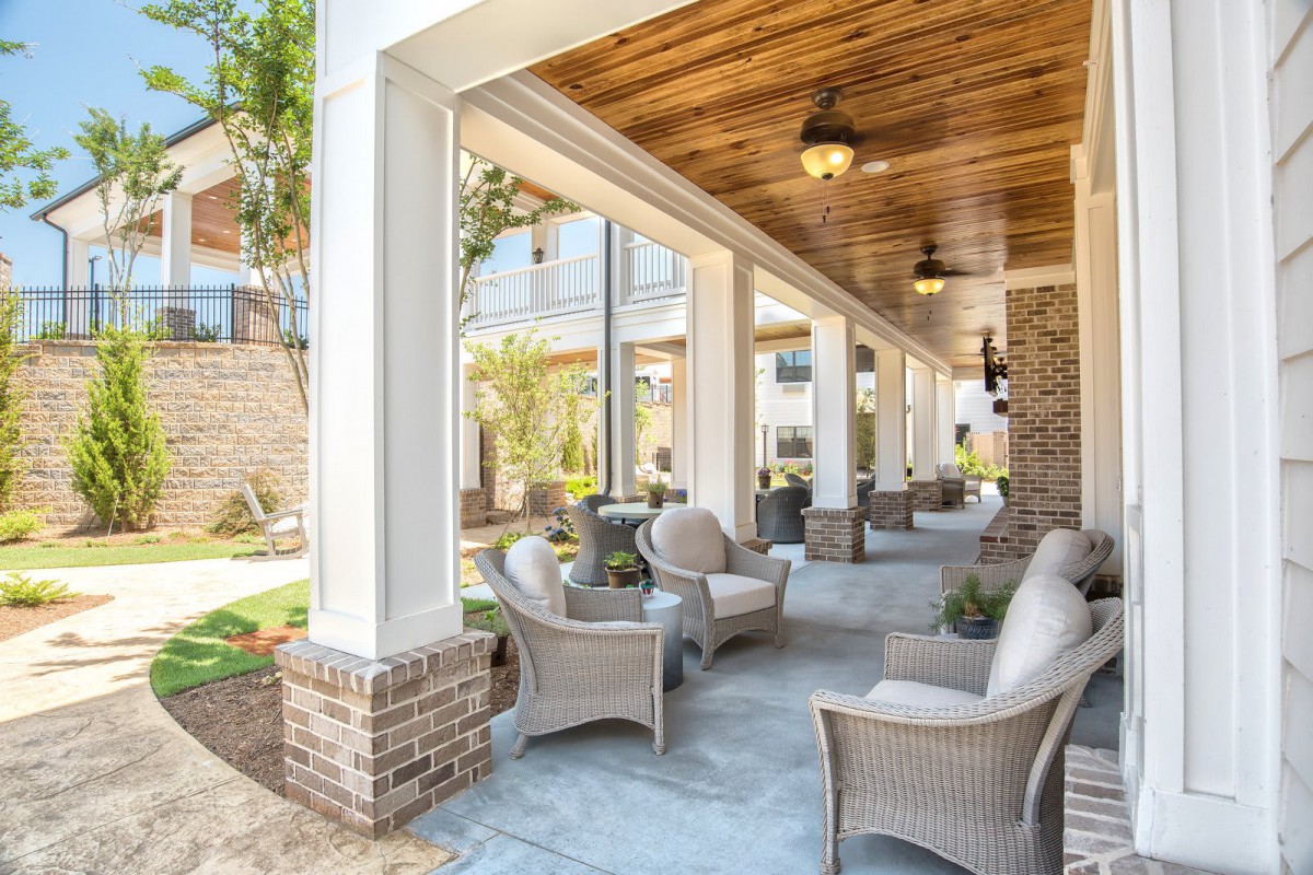 A beautiful covered patio with wicker seating and lush landscaping.