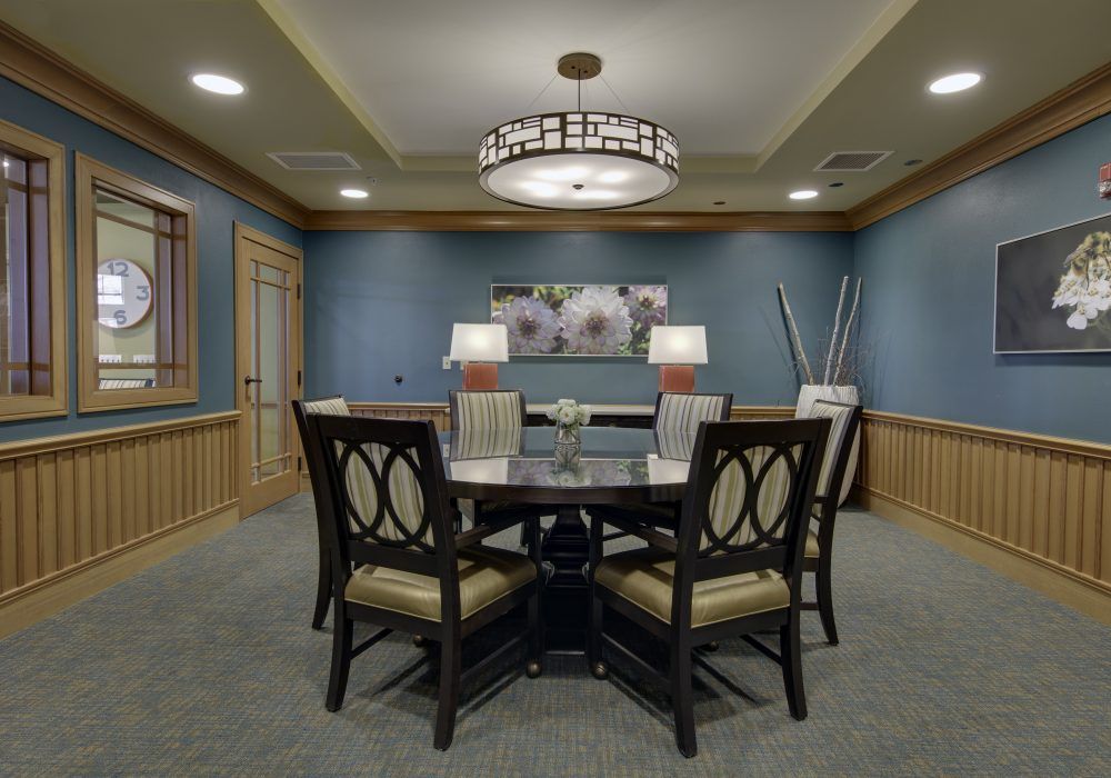 A well-decorated dining room with a round table and chairs, elegant lighting, and tasteful wall decor.