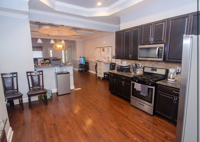 Spacious kitchen with modern appliances and hardwood flooring leading to a dining area.