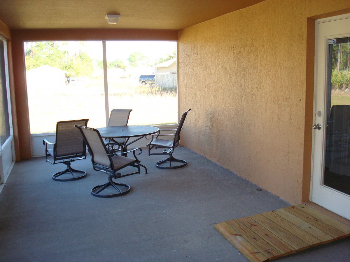 A covered patio with a table and chairs, enclosed by a screen.