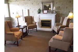 A cozy living room with armchairs arranged around a fireplace.