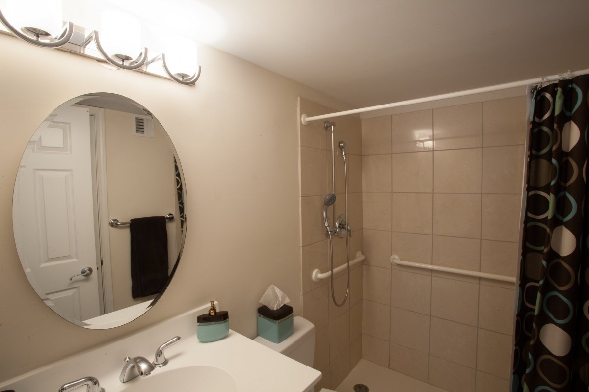 A modern bathroom featuring a shower area, sink with a large mirror, and ambient lighting.