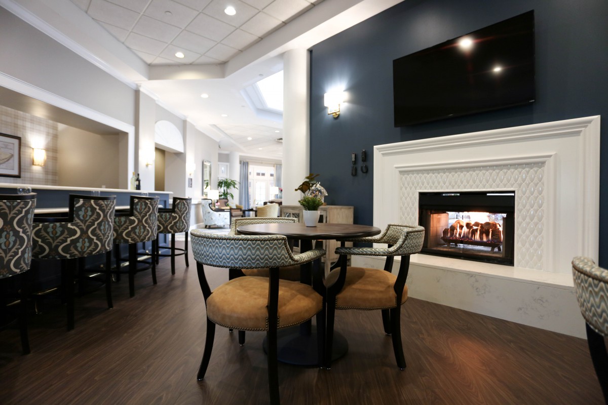 A contemporary living and dining area featuring a cozy fireplace, wooden flooring, and modern furnishings.