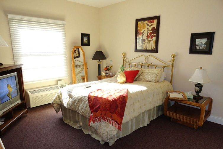 A cozy bedroom with a neatly made bed, decorative pillows, and artwork on the wall.
