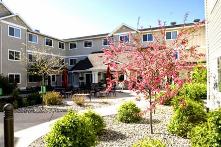 A charming residential building surrounded by beautiful landscaping and blooming flowers.