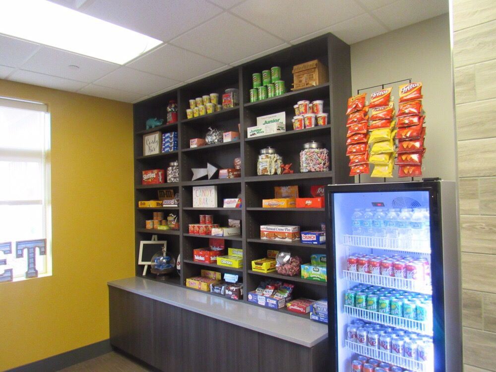A snack area with shelves of various snacks and a refrigerated vending machine filled with beverages.
