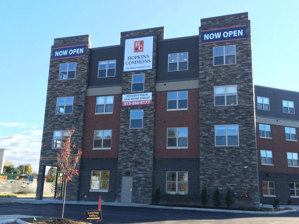 A modern hotel building featuring stone and brick facade with 'Now Open' signs.