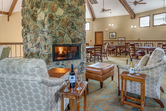 A cozy lounge area with a fireplace, comfortable seating, and a bottle of wine on the table.