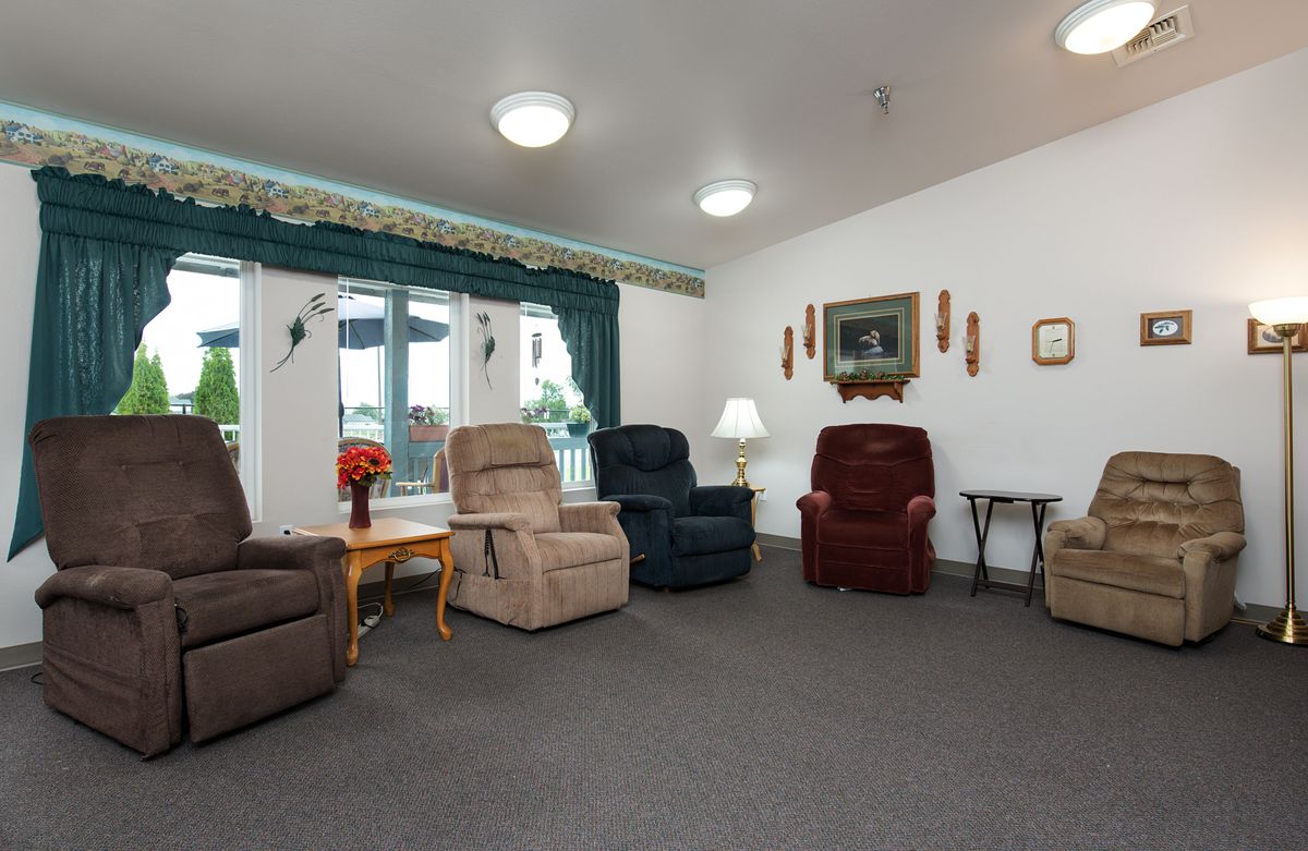 A cozy living room with several comfortable armchairs arranged around a table, decorated with lamps and artwork on the walls.