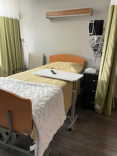 A patient room in a hospital, featuring a bed, medical equipment, and curtains for privacy.