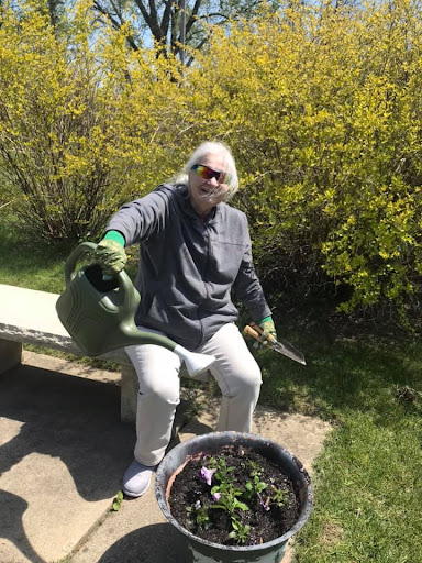 An individual enjoys gardening on a sunny day, tending to their plants with a watering can.