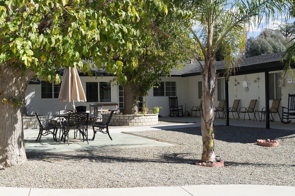 A peaceful backyard patio area with outdoor furniture and trees.