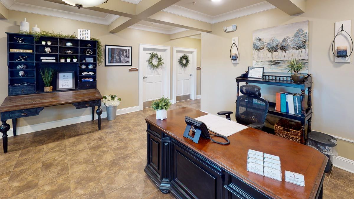 A welcoming office reception area with a desk, computer, and decorative elements including wall art and plants.