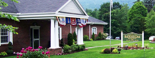 A beautifully landscaped house adorned with patriotic banners, welcoming guests with its charming front porch.
