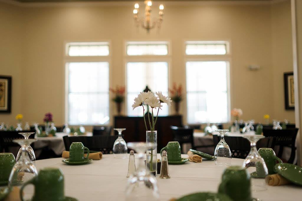 An elegantly set dining table with a central floral arrangement and soft natural lighting.