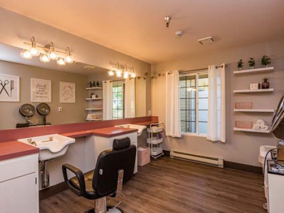 A cozy hair salon with a stylish interior featuring a large mirror, comfortable salon chair, and warm lighting.