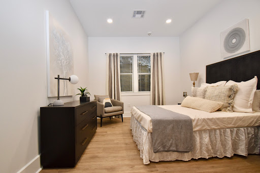 A modern and cozy bedroom featuring a neatly made bed, stylish furniture, and natural light filtering through the curtains.
