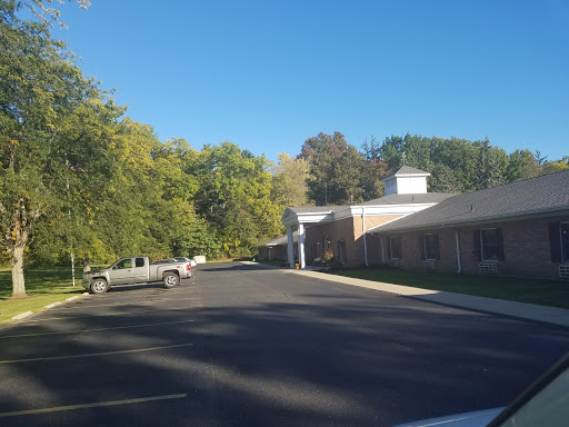 A serene view of a building along a tree-lined road under a clear blue sky.