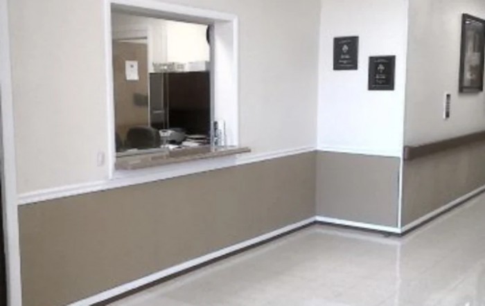 A minimalist waiting area featuring a reception window and neutral-toned walls.