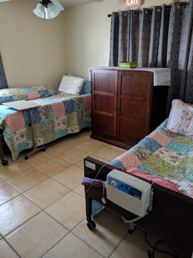 A cozy hospital room featuring two beds with colorful quilts and a wooden wardrobe.