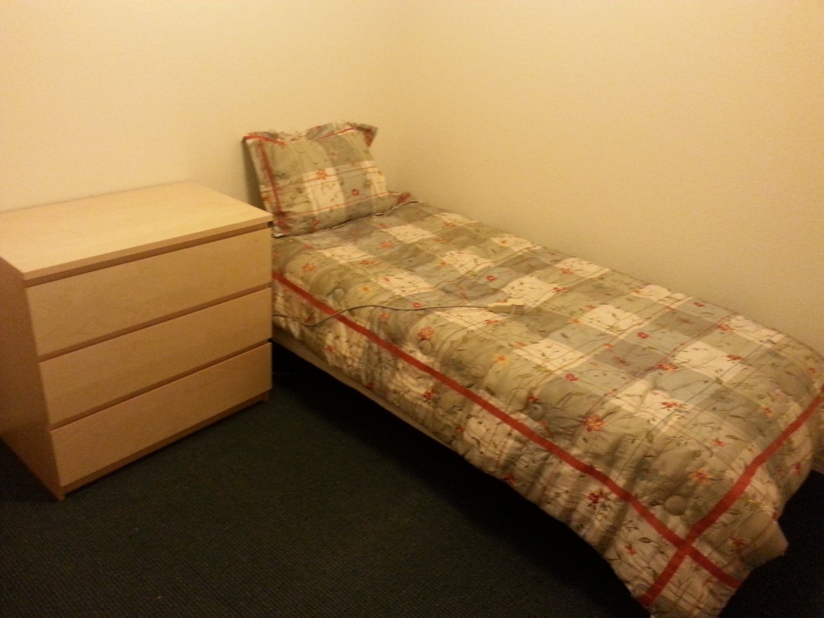 A minimalist bedroom with a single bed and a small dresser.