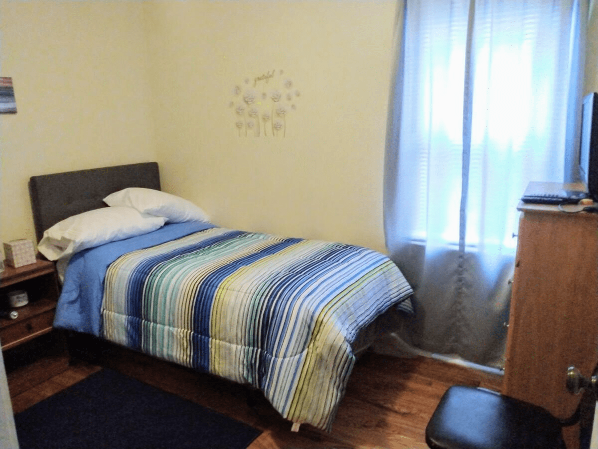 A cozy bedroom with striped bedding and a window with curtains.