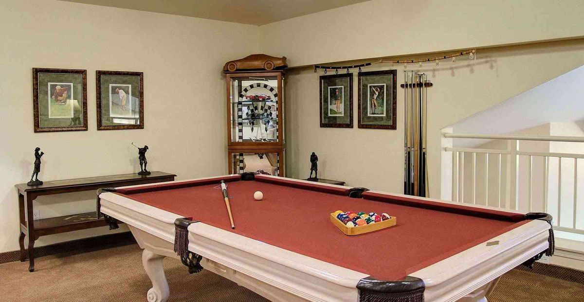 A cozy game room featuring a red felt pool table with cue sticks and billiard balls ready for play.