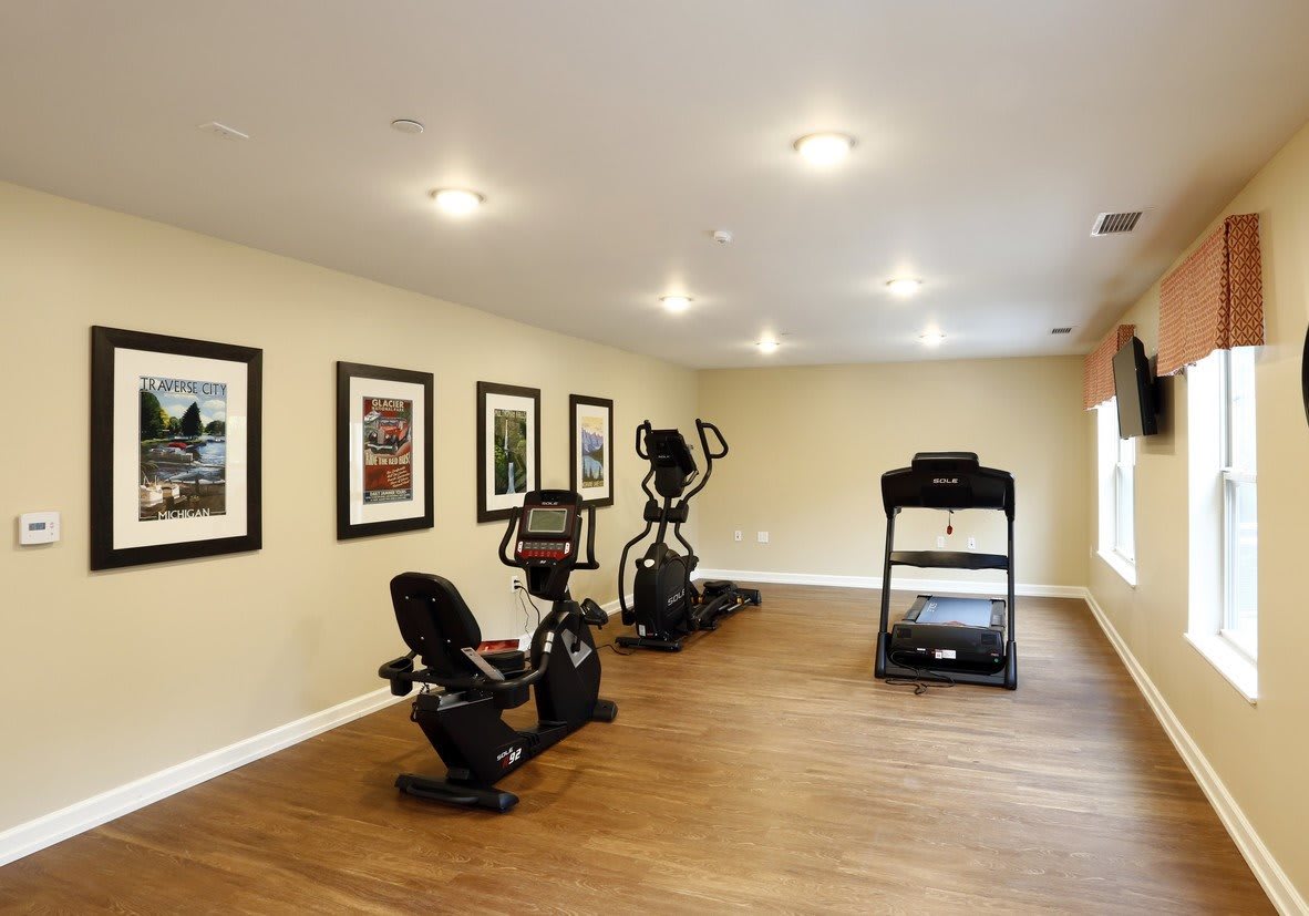 A home gym featuring a treadmill, stationary bike, and elliptical machine in a spacious room.