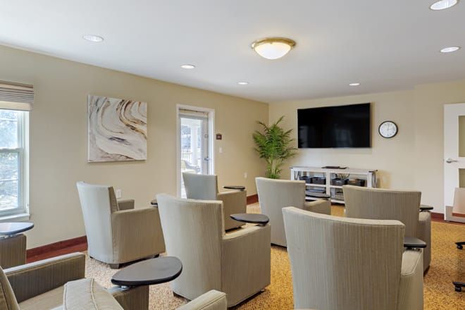 A modern seating area with comfortable chairs and a large television on the wall, suitable for meetings or relaxation.