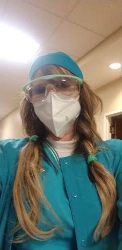 A healthcare professional wearing personal protective equipment (PPE), including a face mask and safety glasses, ready for work.