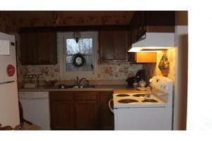 A cozy kitchen with wooden cabinets, a stove, and a window above the sink.