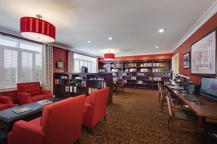 A cozy library with red chairs and wooden bookshelves, creating a warm reading environment.