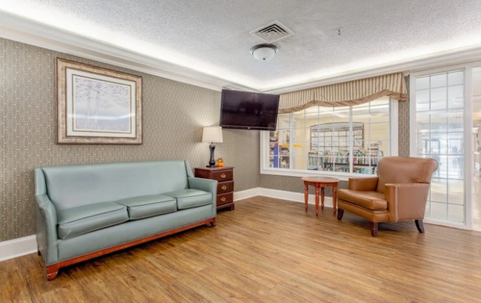 A cozy living room with a sofa, armchair, and a wall-mounted TV.