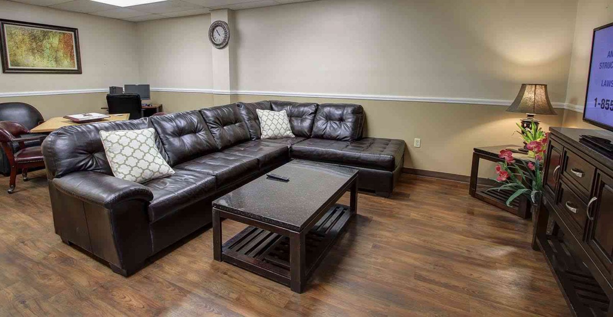 A comfortable living room with a leather sectional sofa and wooden coffee table on hardwood floors.