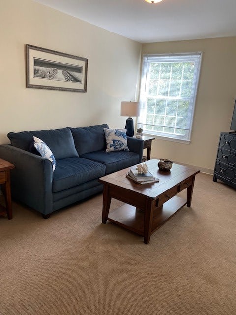 A cozy living room featuring a blue sofa, wooden coffee table, and a lamp by the window.