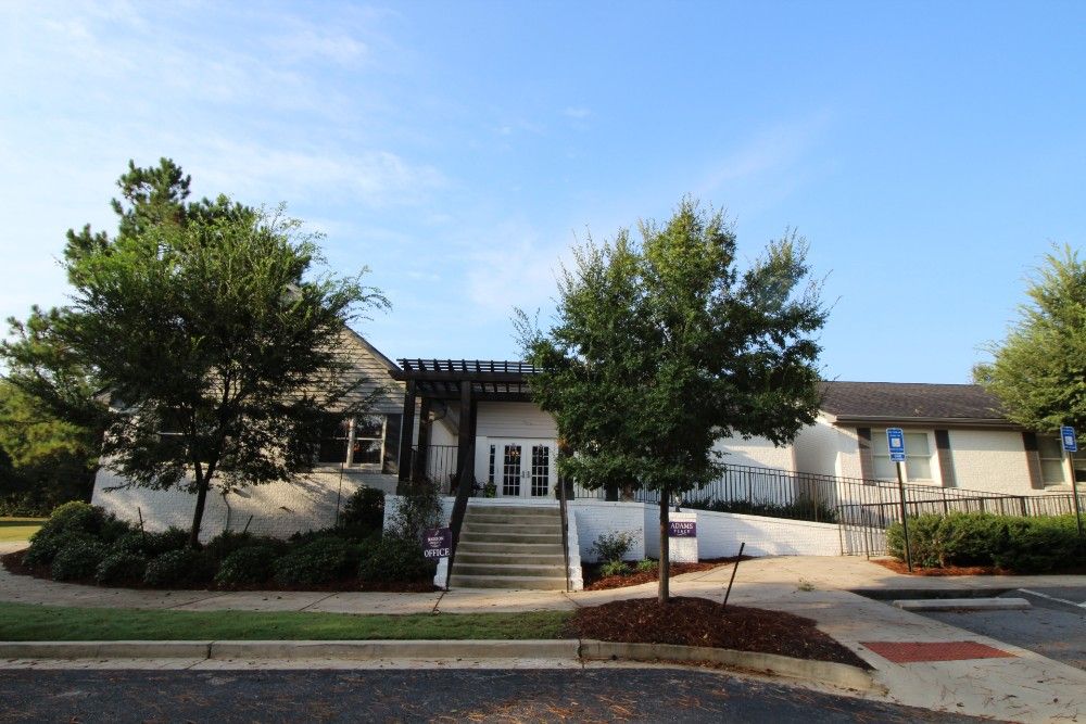 A suburban house with a front yard and trees under a clear sky.
