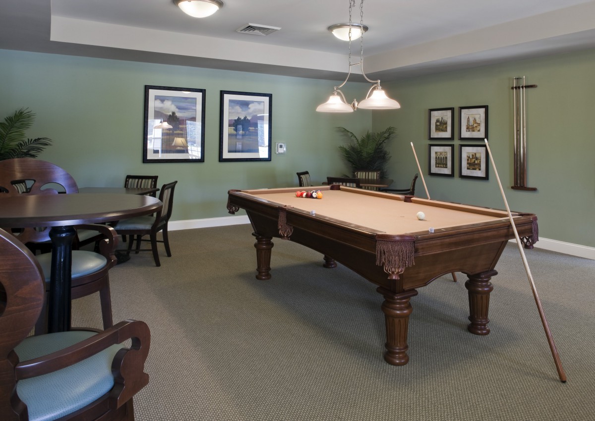 A cozy game room featuring a pool table, classic furniture, and elegant wall art.
