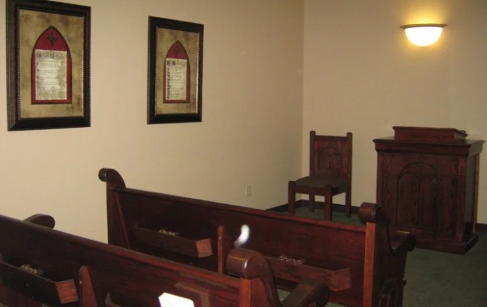 Interior view of a church showing wooden pews and chairs.